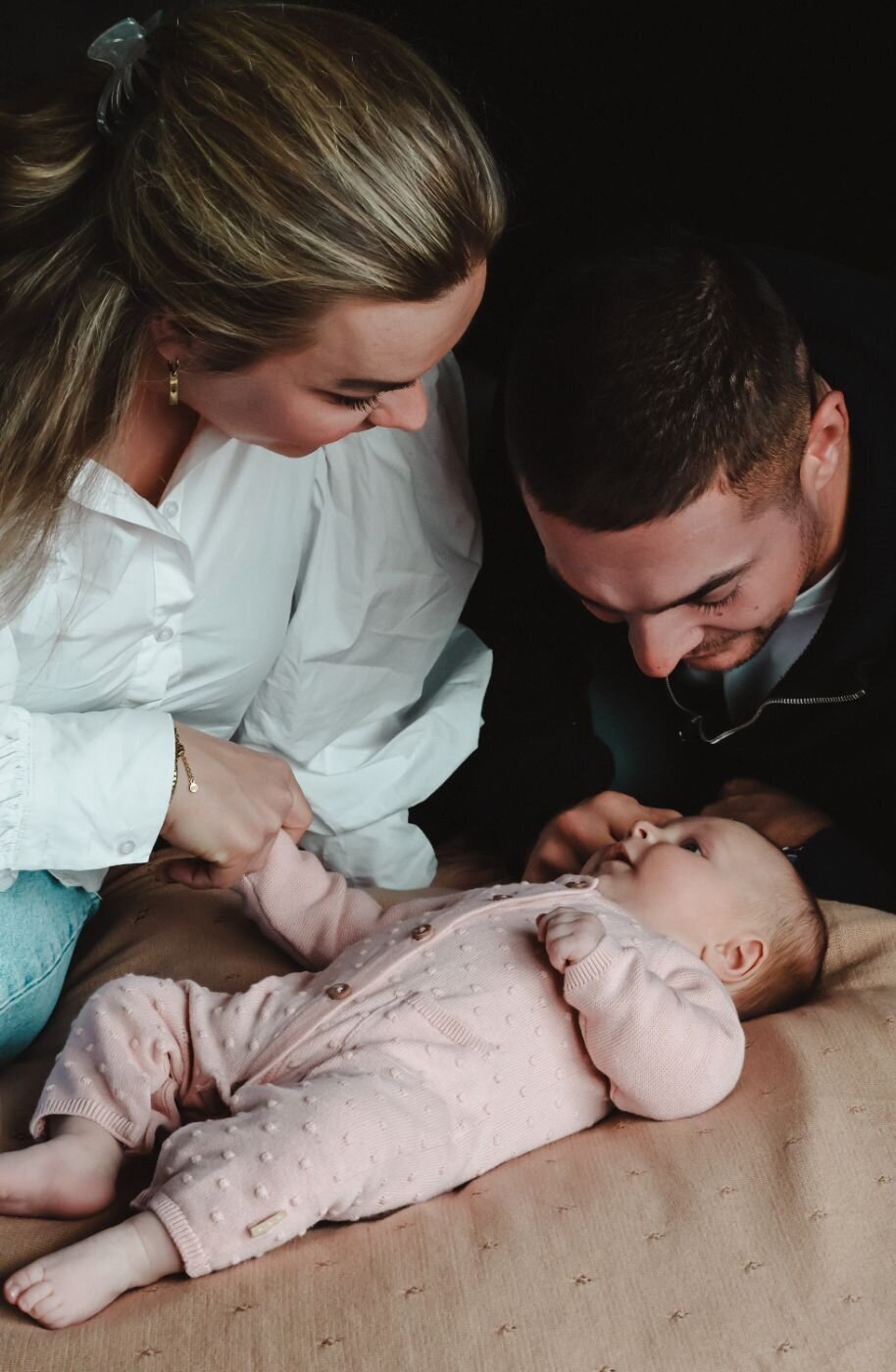 ouders die naar hun baby kijken en moeder die de hand van de baby vasthoudt