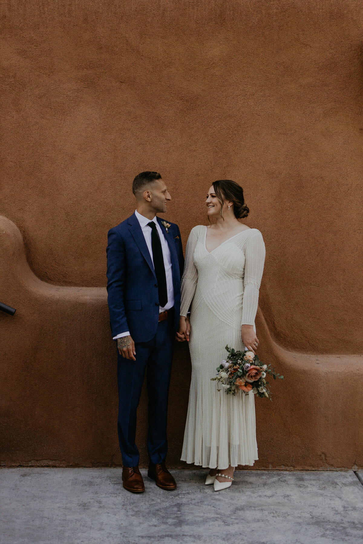 bride and groom in front of an adobe style building in Santa Fe