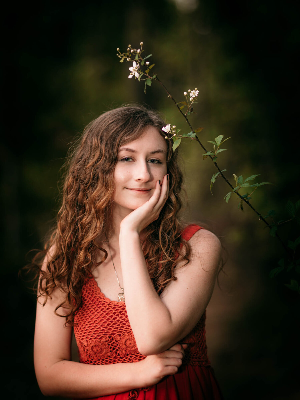 An artistic senior portrait of a girl in an orange dress with flowers above her head.