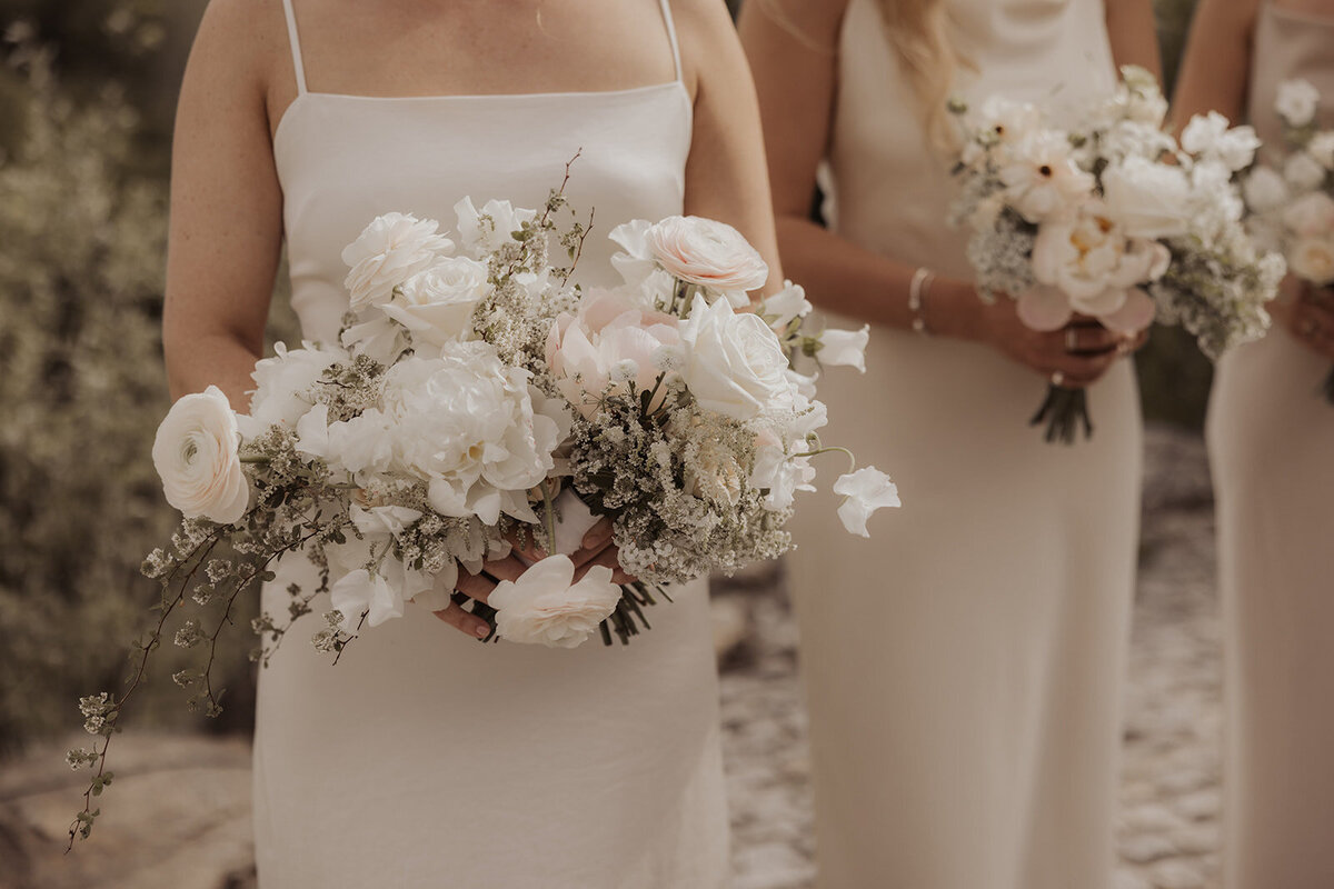 A bride holds a lush, elegant bouquet of white flowers at Chateau St-Agnes.