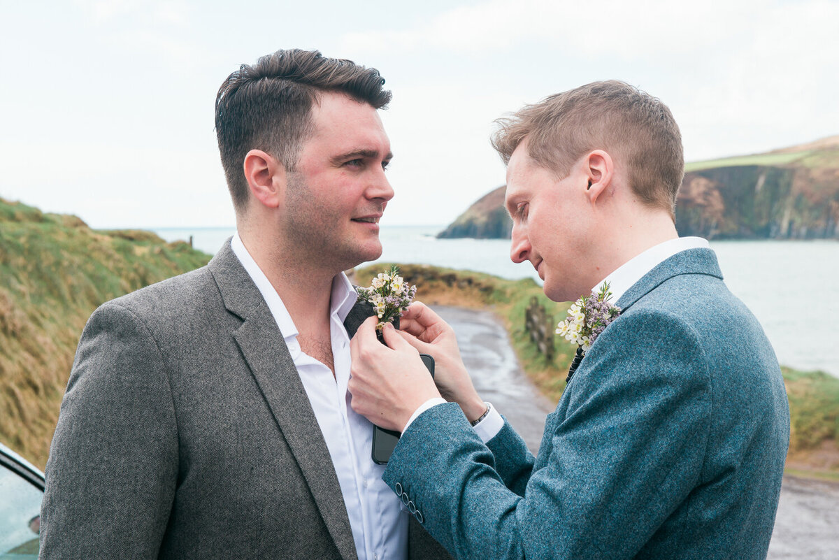 Groom putting buttonhole on his partner's jacket