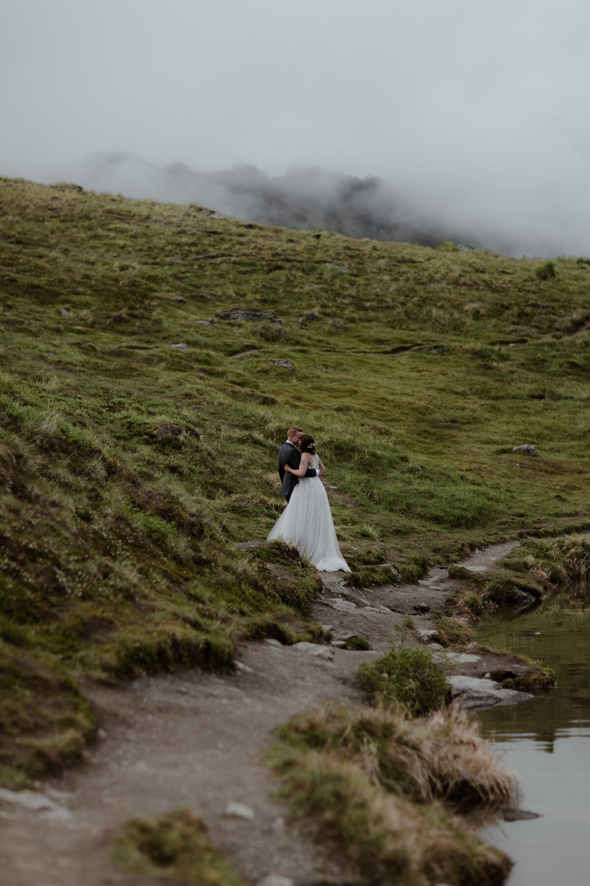 bride and groom posing on hillside