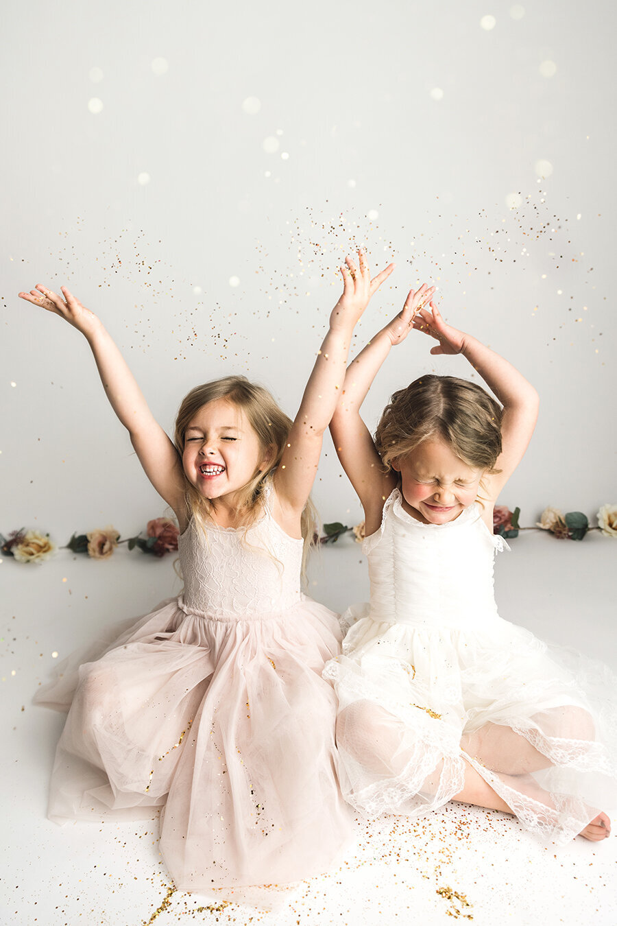 Two best friends throwing glitter over their heads in Fort Collins photo studio