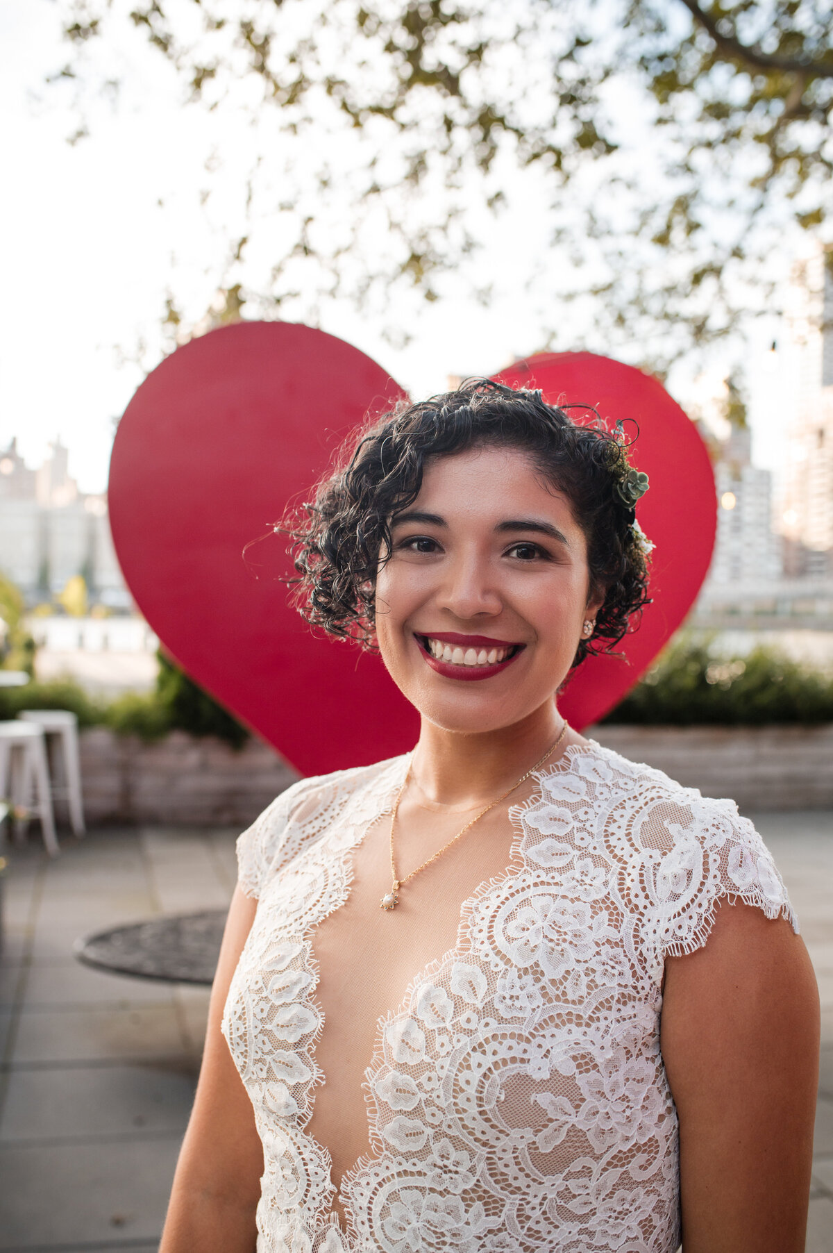 Beautiful Latina bridal portrait with curly black hair, red lipstick in her lacy wedding dress.