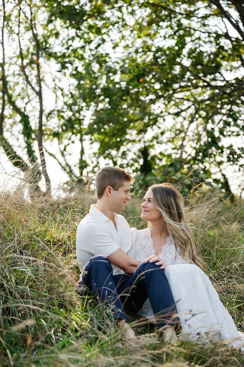 couple sitting on bluff at discovery park seattle for engagement portrait