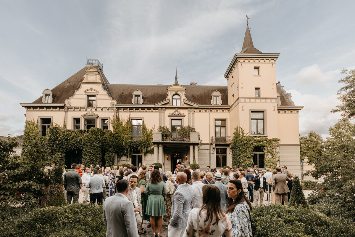 Gasten verzamelen zich bij een prachtig kasteel om het bruidspaar te vieren op deze unieke trouwlocatie.