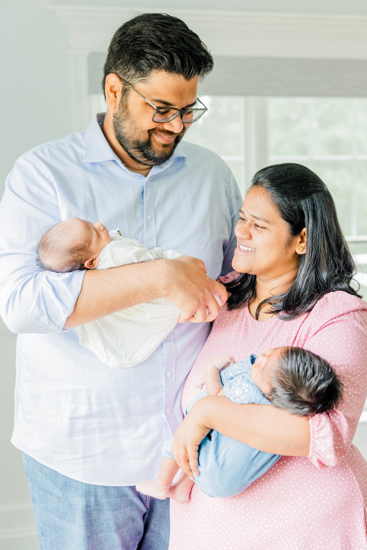Mother and father each holding  one of two twins in a Boston Newborn Session
