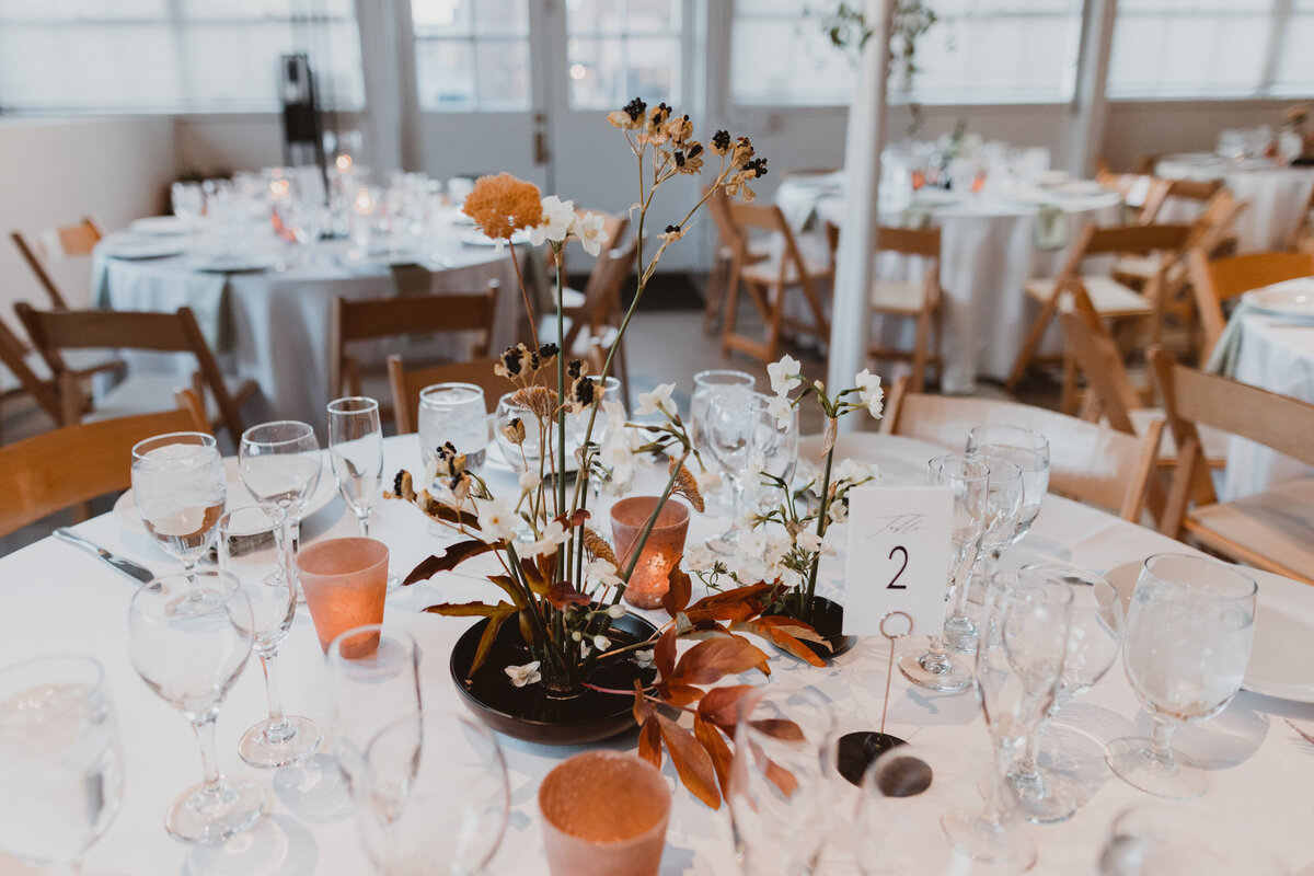 Centerpiece with copper votive candles and fall colored floral arrangements.