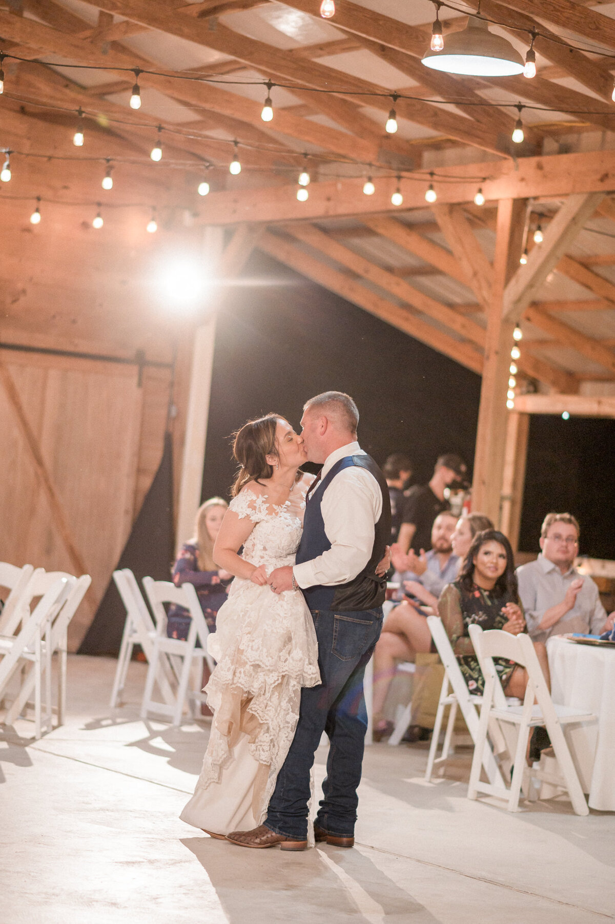 The couple kiss as their first dance comes to and end during their rustic wedding reception