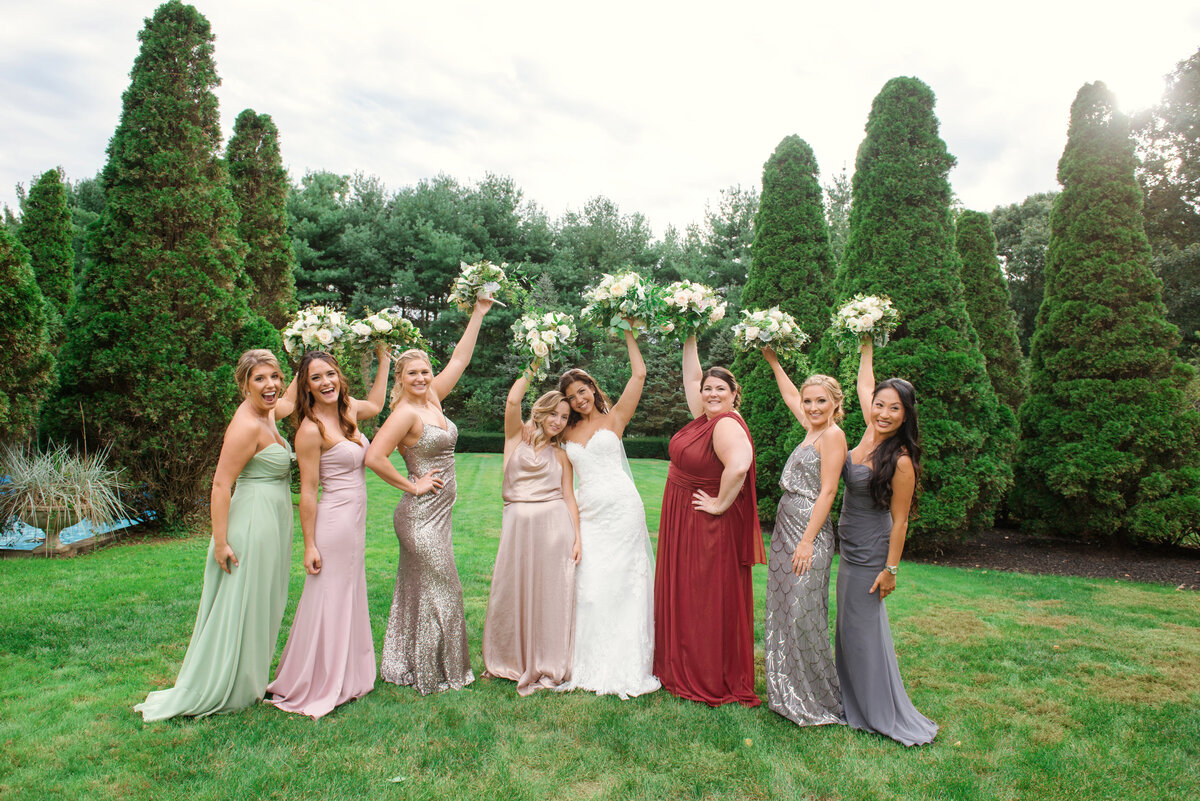 photo of bridesmaids holding their bouquets in the air with bride from wedding at The Carltun