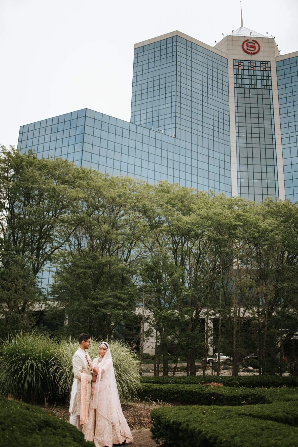 South Asian Bride and groom holding hands surrounded by greenery in New Jersey.