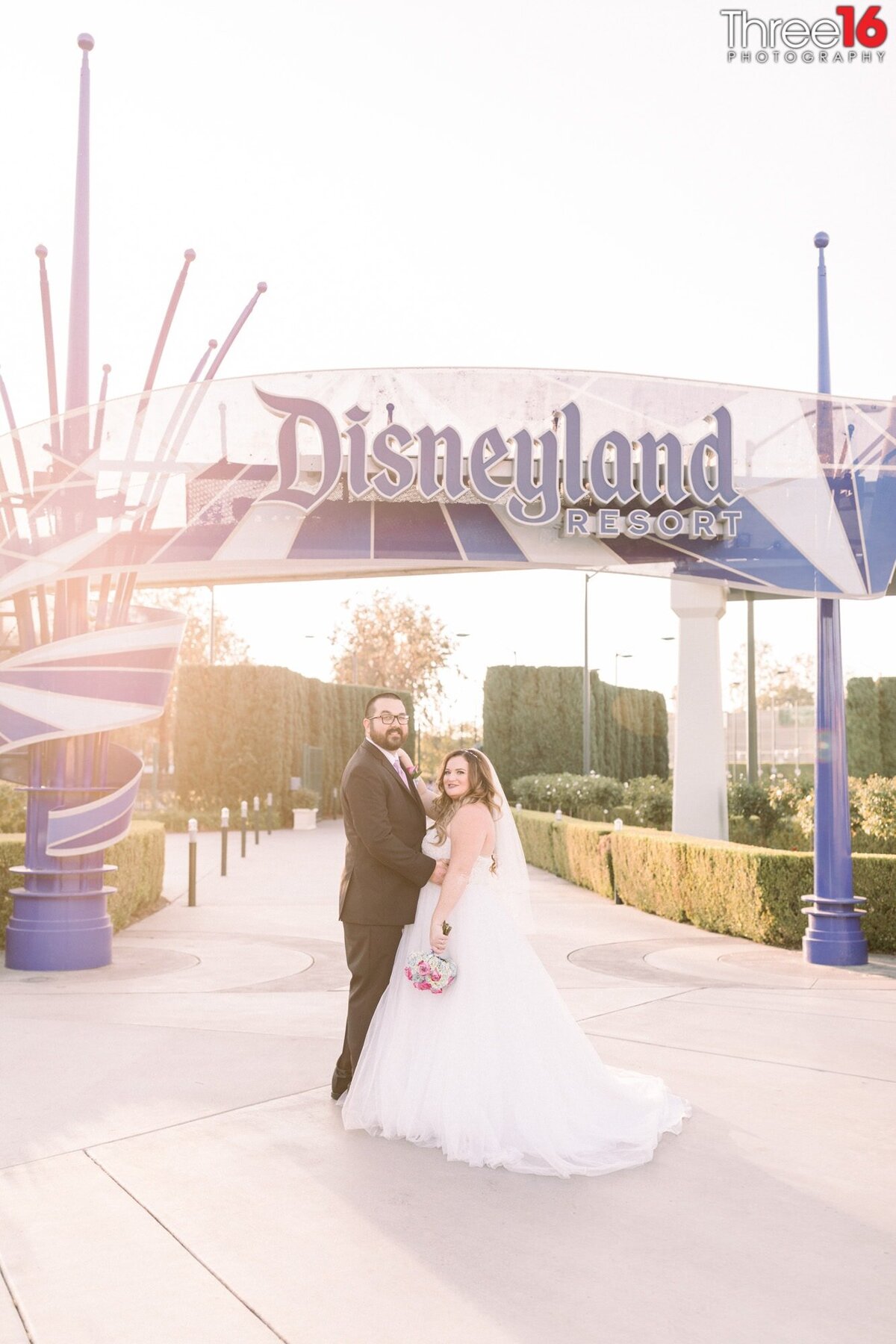 Newly married couple pose together in front of the entrance to Disneyland