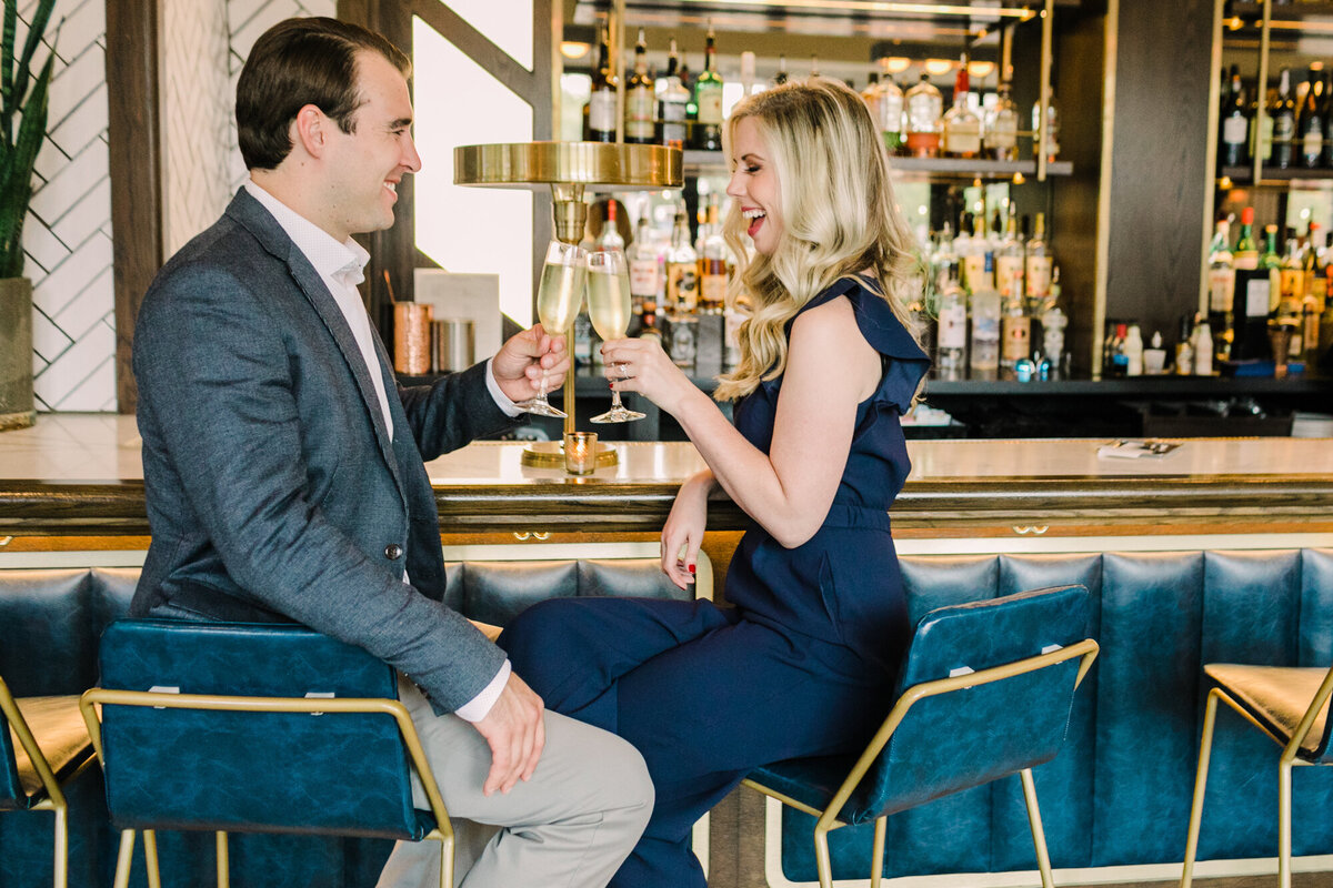 A couple clinks glasses as they enjoy a sip of champagne during their engagement photo session in Chicago