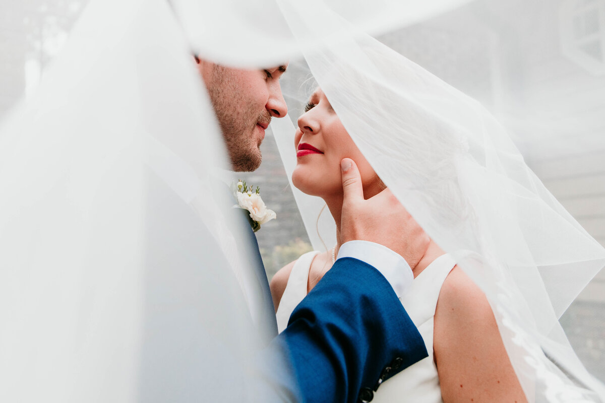 couple poses under veil on wedding day