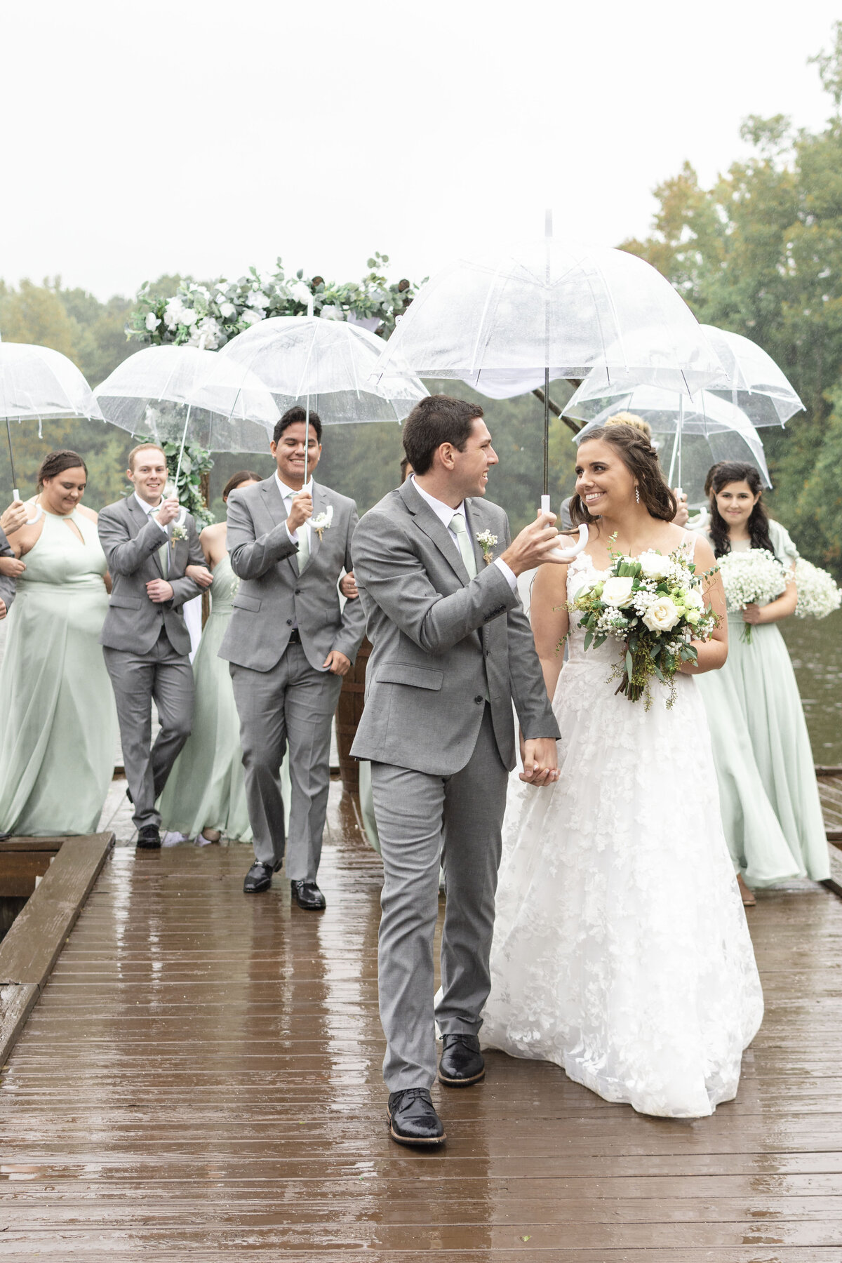 Bride & groom with their wedding party in the rain at Carolyn Baldwin Lake