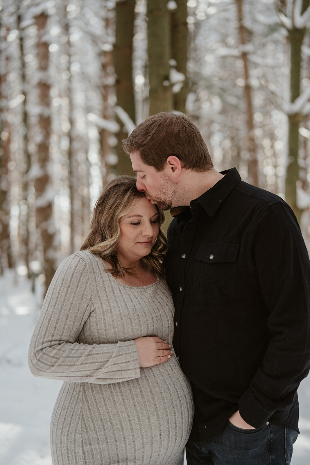 A dad kissing his pregnant wife on the forehead during their maternity session at Al Sabo Land Preserve in Kalamazoo, MI
