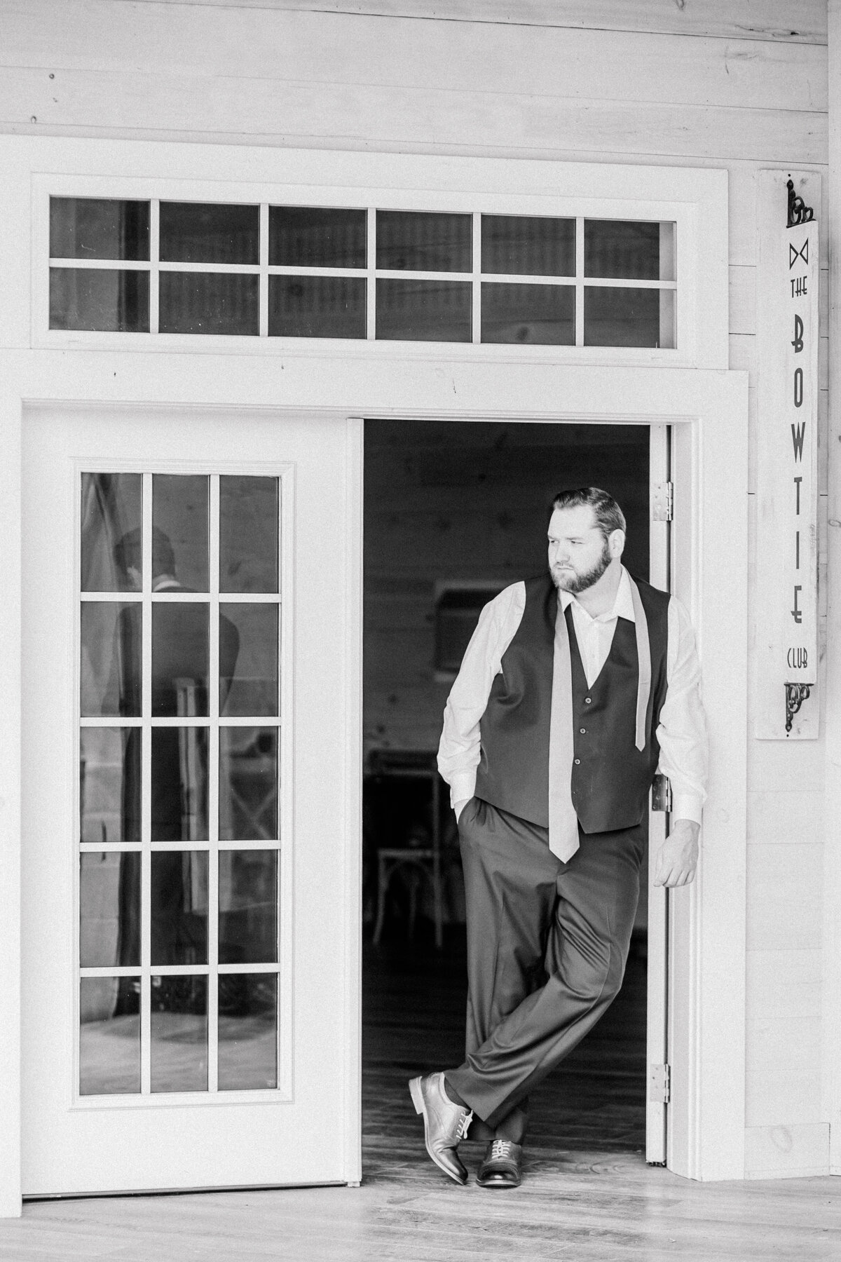 Groom leaning against doorway with his tie undone during getting ready