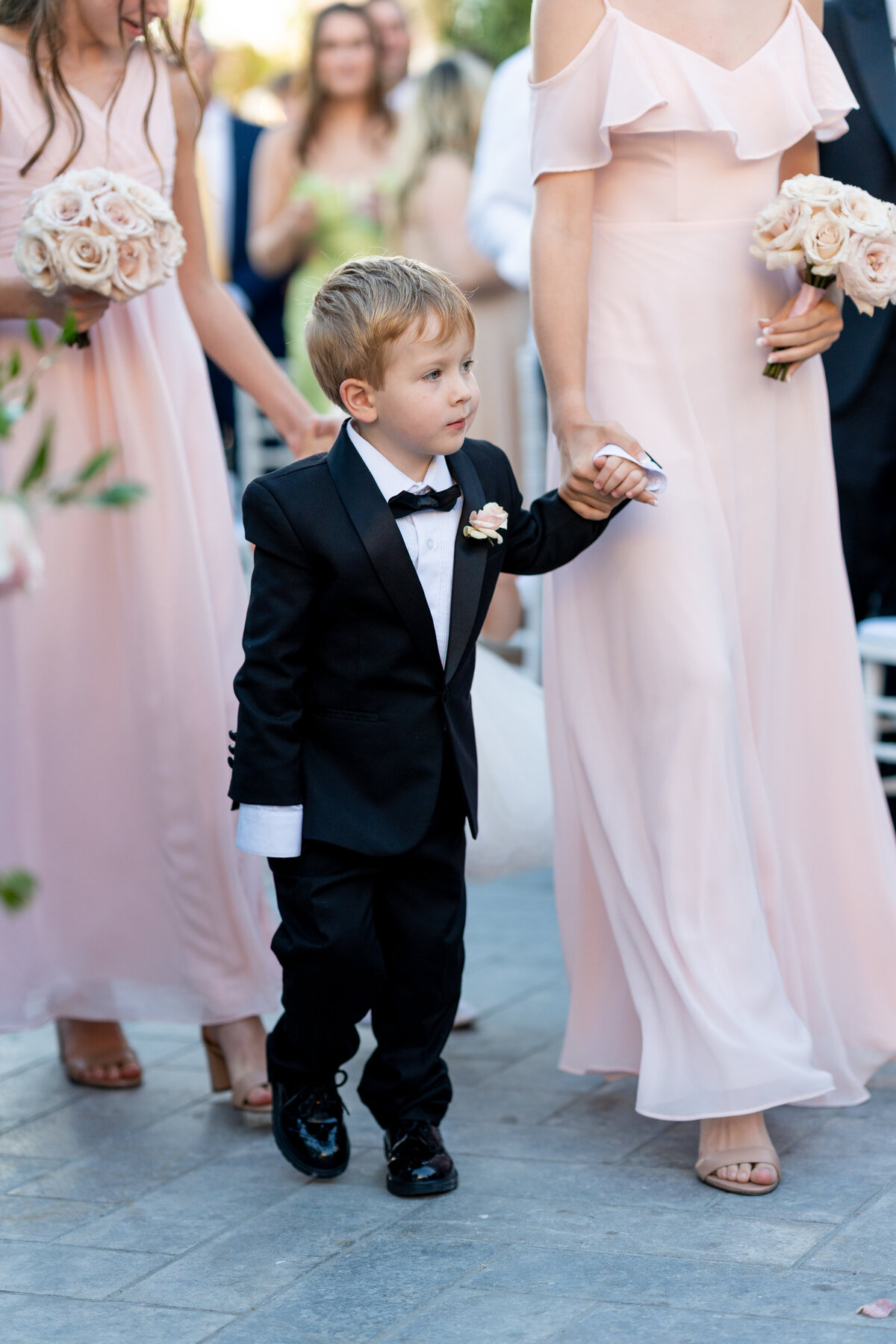 ring bearer in black tuxedo with pink boutonniere