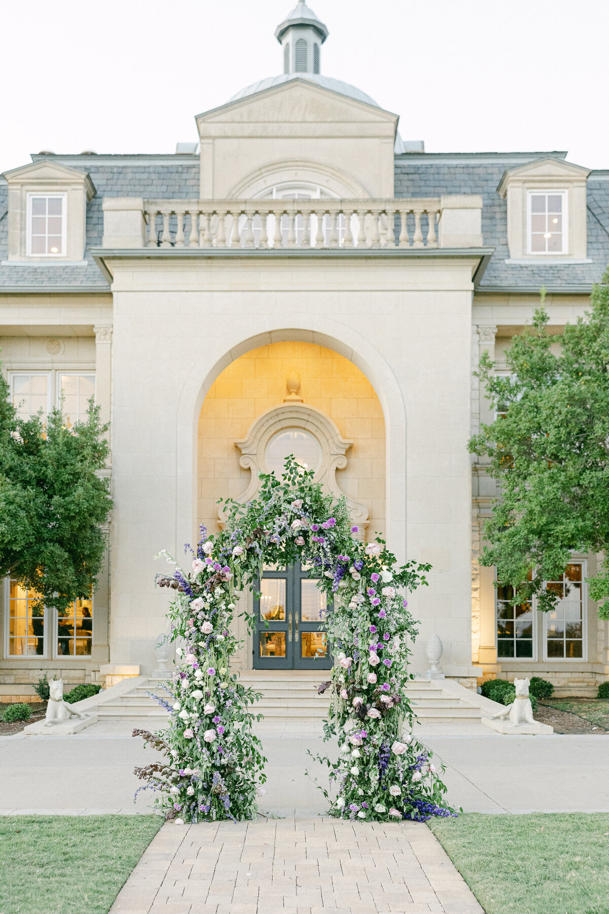 a floral arch in front of a grand wedding venue