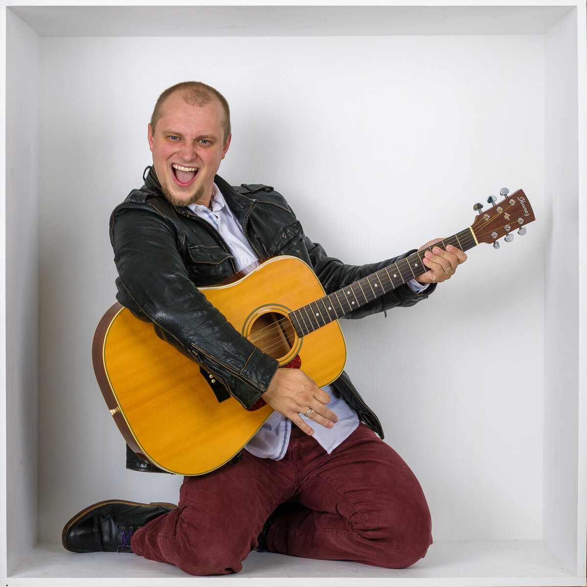 Headshot and branding photographer Travis from Fox & Brazen in  a white box with a guitar