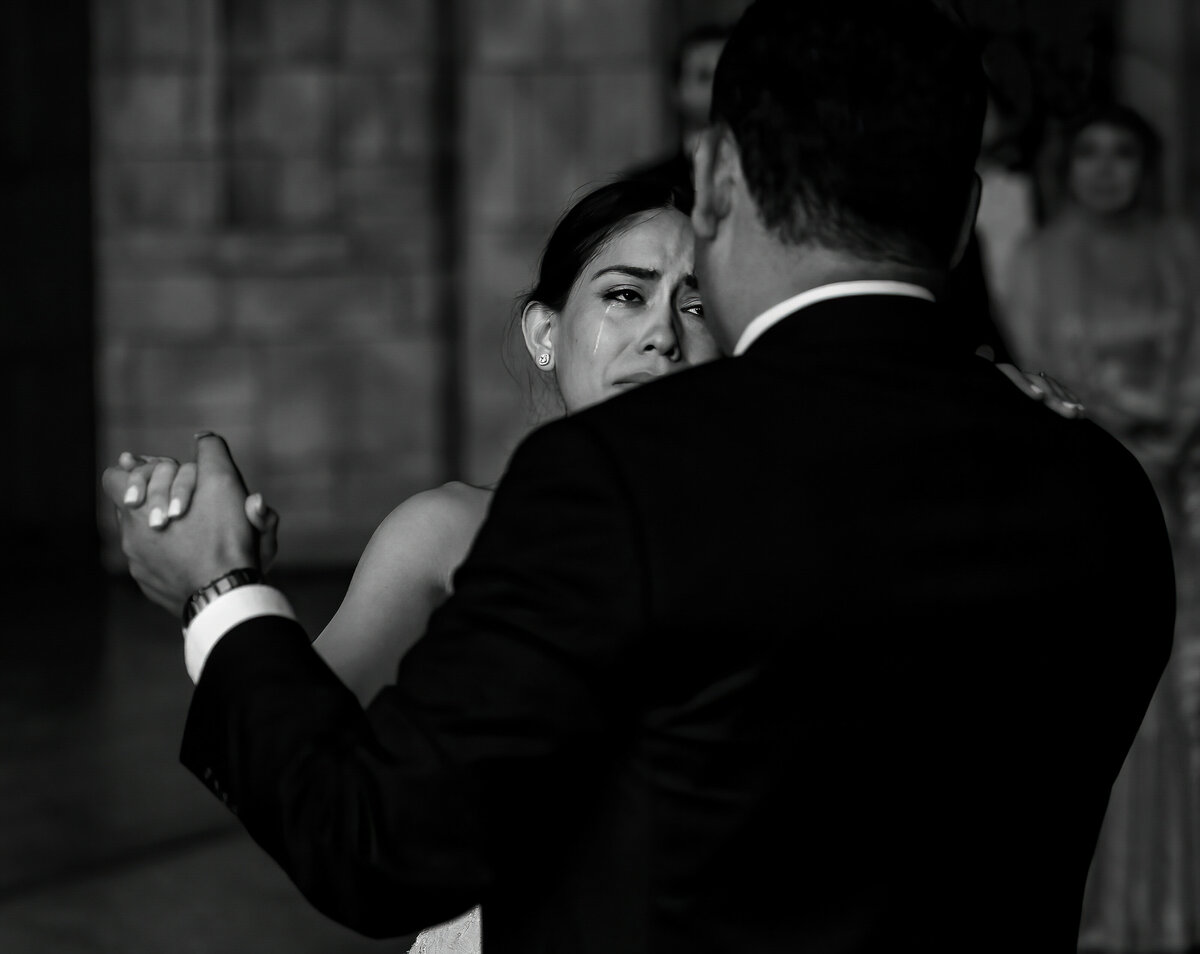 A bride sheds a tear as she dances.