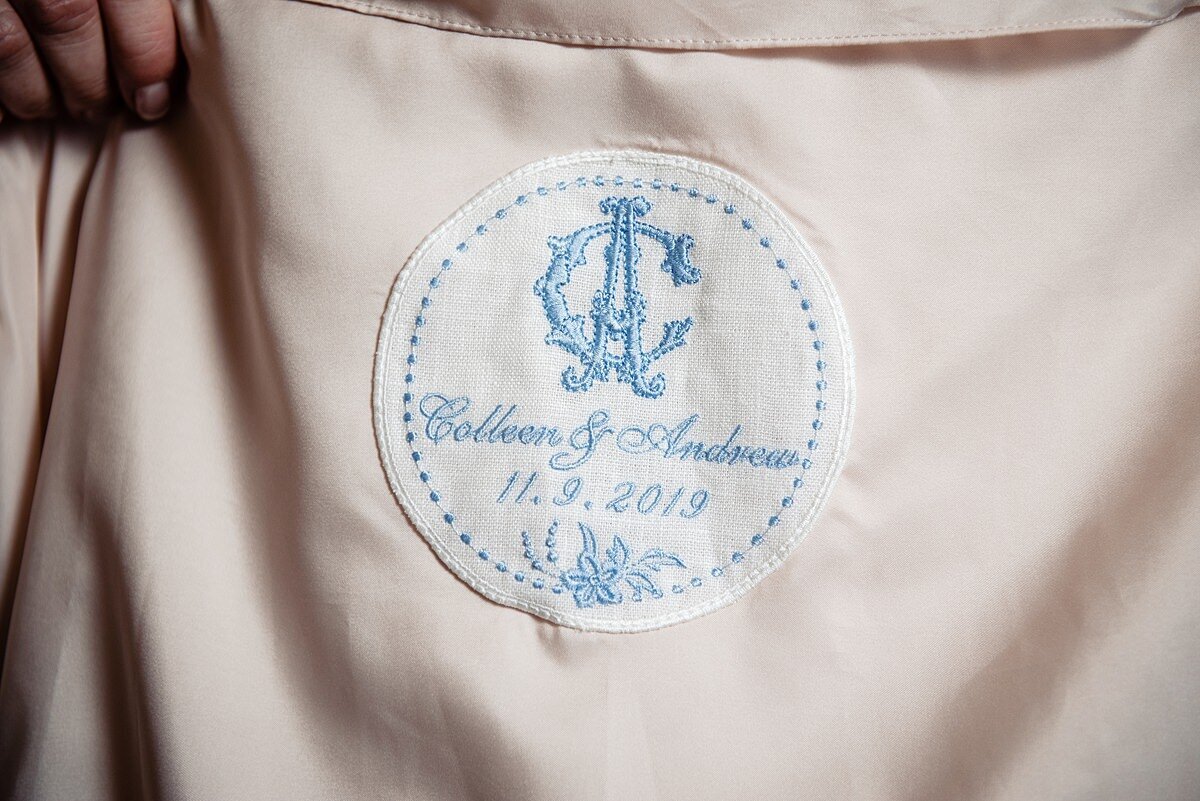 Detail of the bride and groom's initials, names and wedding date monogramed in blue thread inside the bride's wedding gown.