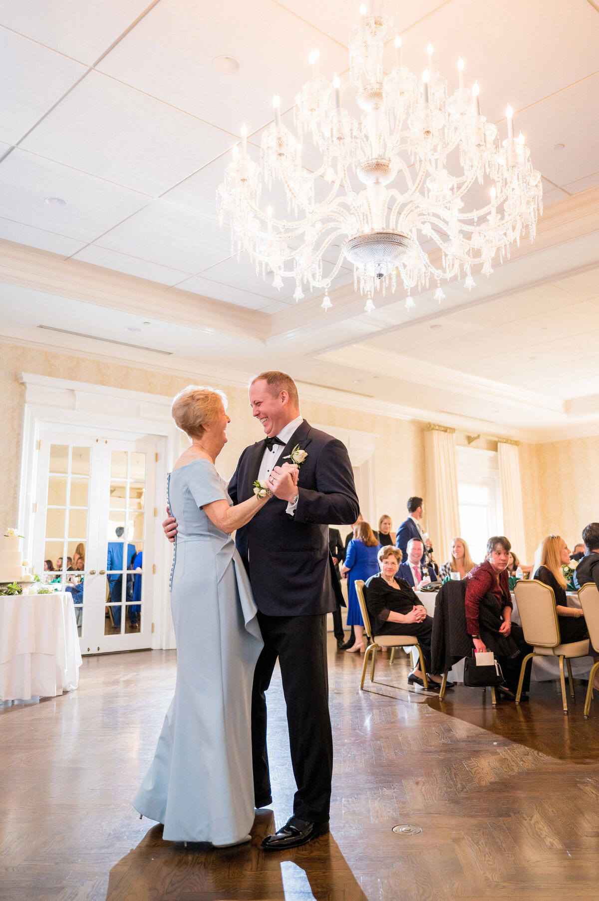 mother and son dancing together in the ballroom at the pittsburgh field club with a large chandelier