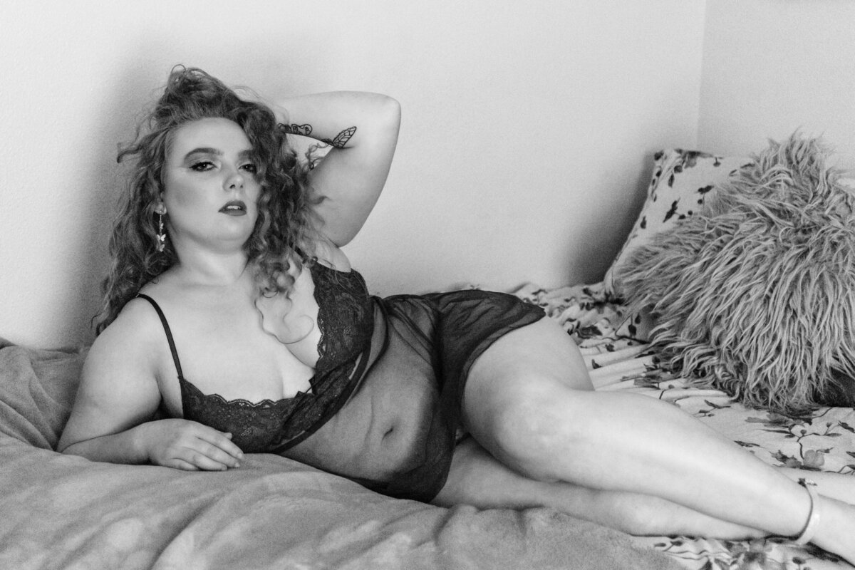 Boudoir photo woman laying on bed in sheer babydoll nighty