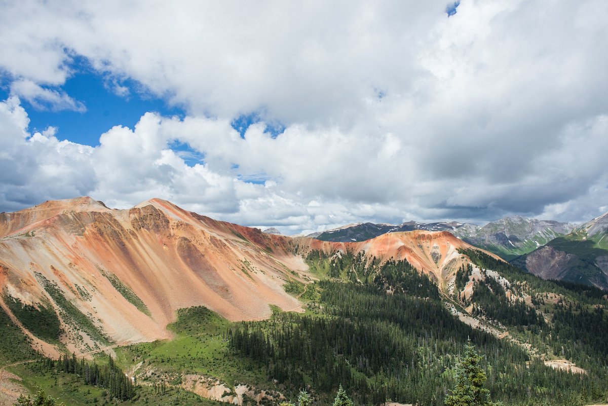The Red Mountain of Silverton and Ouray, Colorado rises out of the green forest landscape.