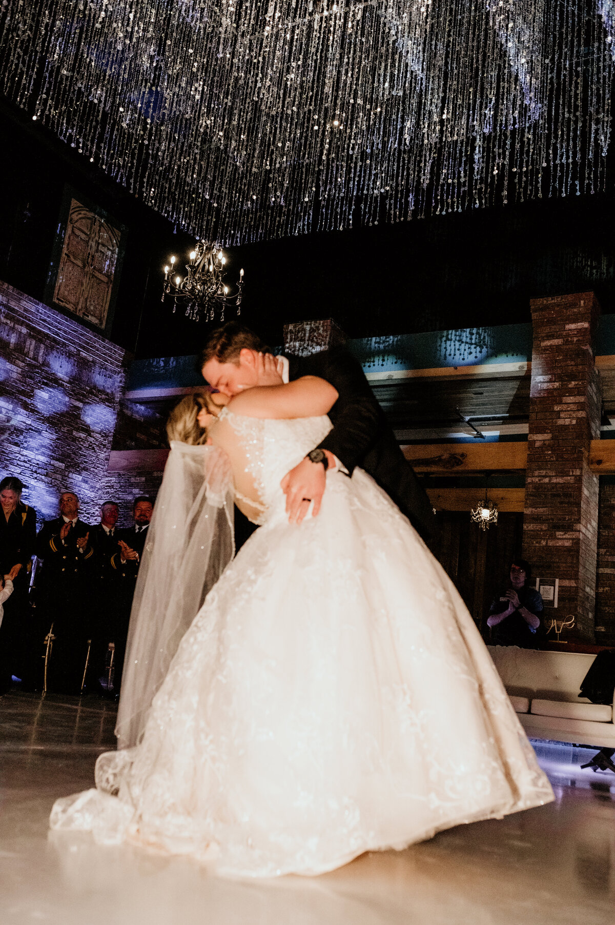 bride and grooms first dance together at their indoor wedding reception with the groom kissing his bride and she dips backwards captured by Little Rock wedding photographer