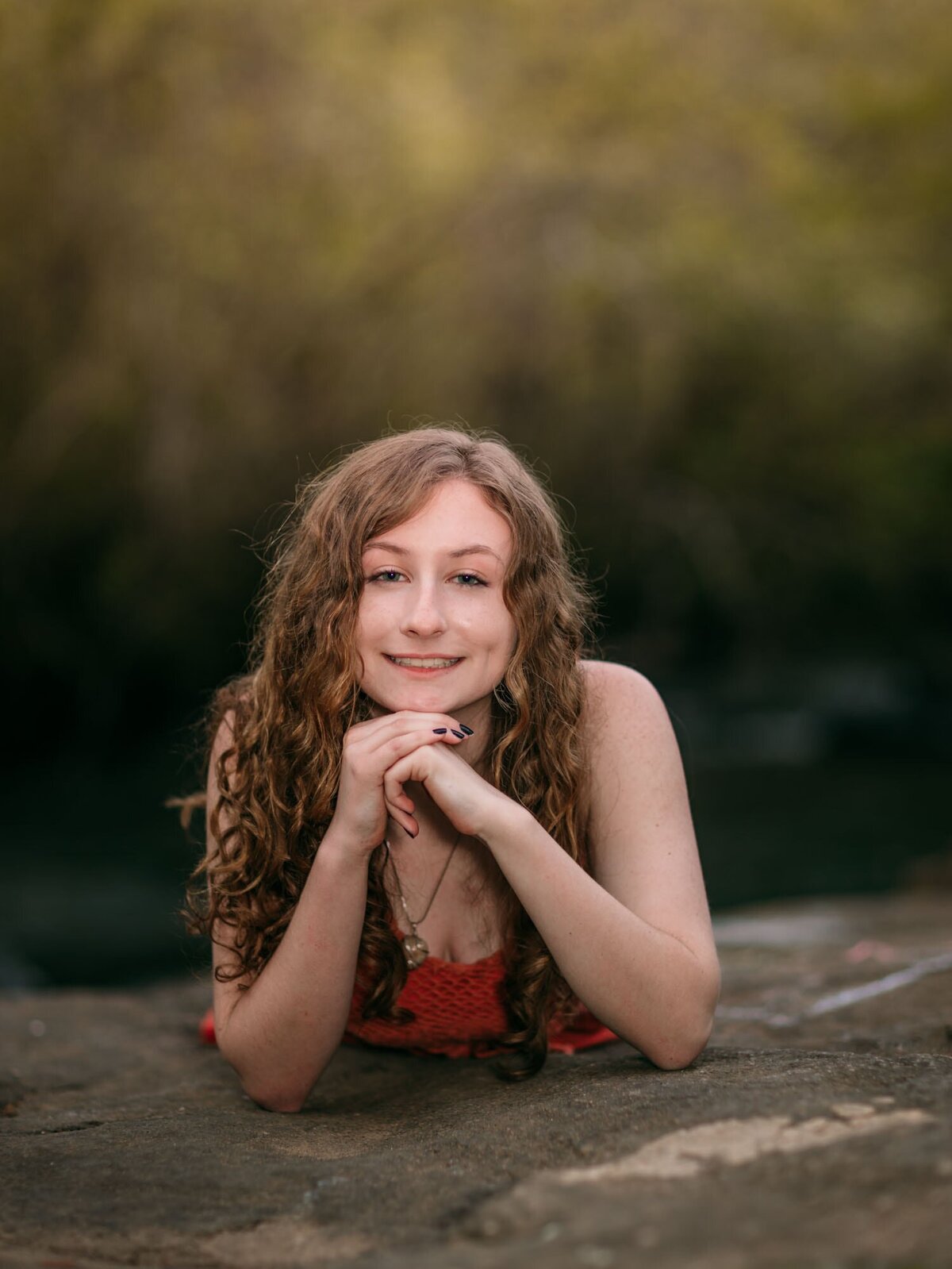 A girl lying on a rock on her elbows with a beautiful smile.