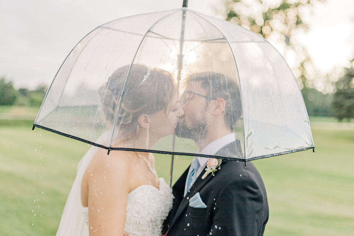 husband and wife kissing under umbrella