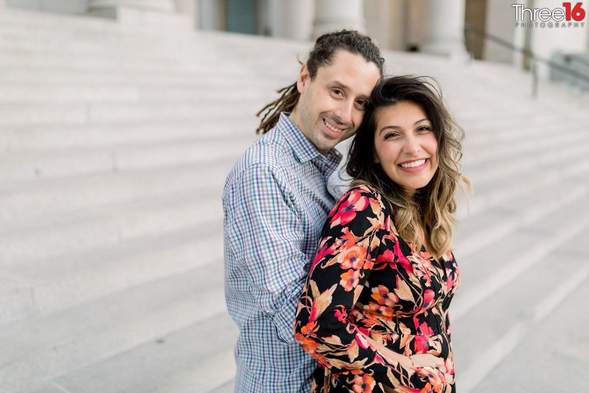 Groom to be holds his Bride from behind on the Los Angeles City Hall steps