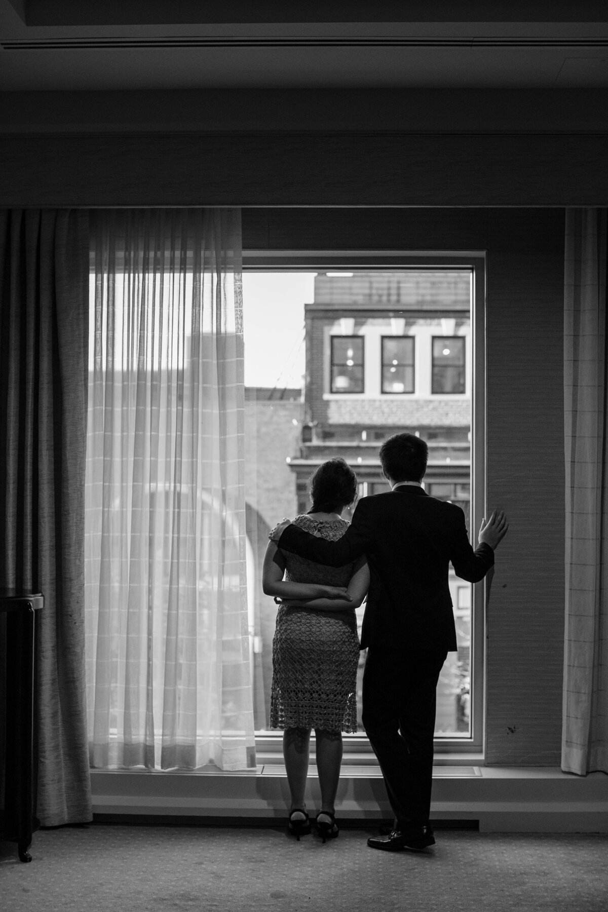 A couple looks out the window during wedding at the Mandarin Oriental Hotel in Boston.