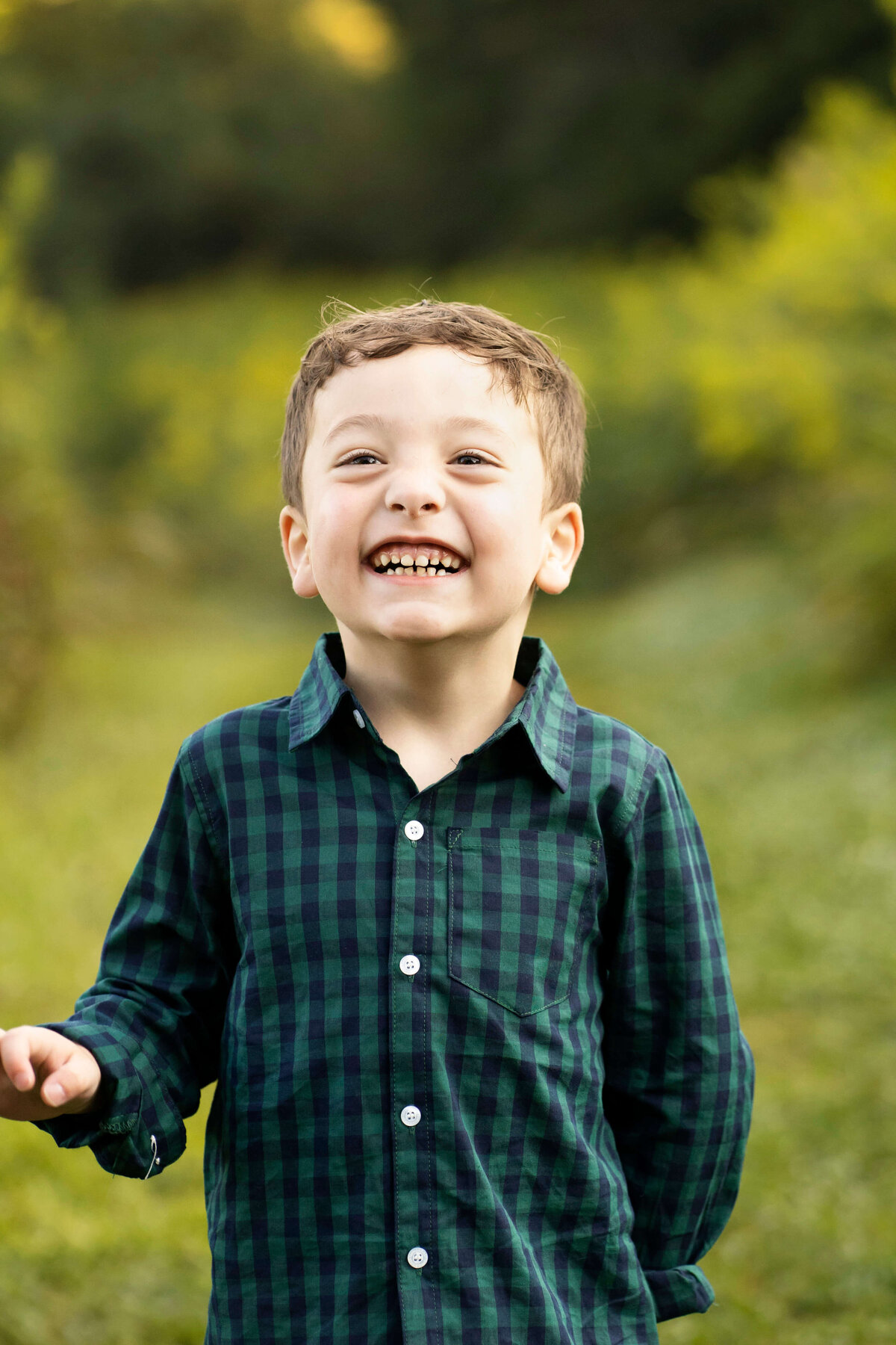 Young boy standing and laughing at camera in a grassy field