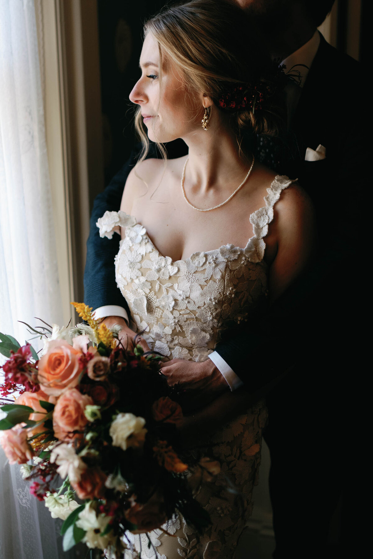 bride looks out window at the brick house shelburne museum with fall florals