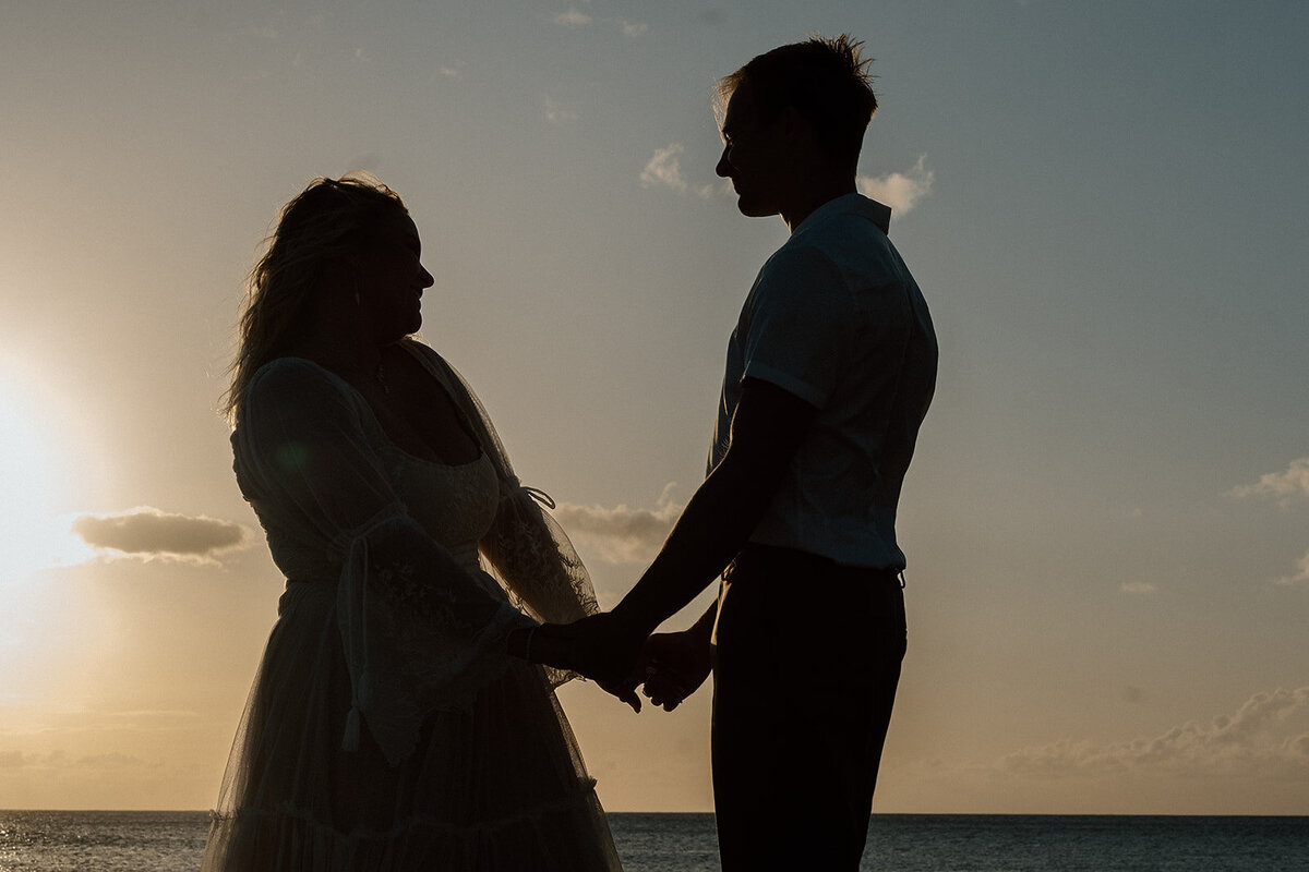 silhouette of bride and groom by the ocean at twilight