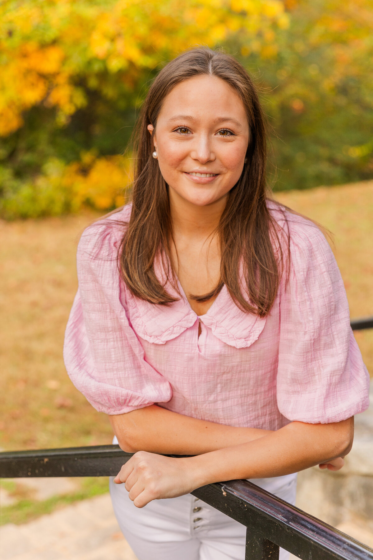 young woman wearing pink top leaning on a  handrail during photo session