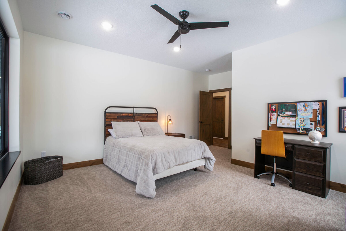Spacious secondary bedroom in custom Elk River home with dark wood accents and neutral tones