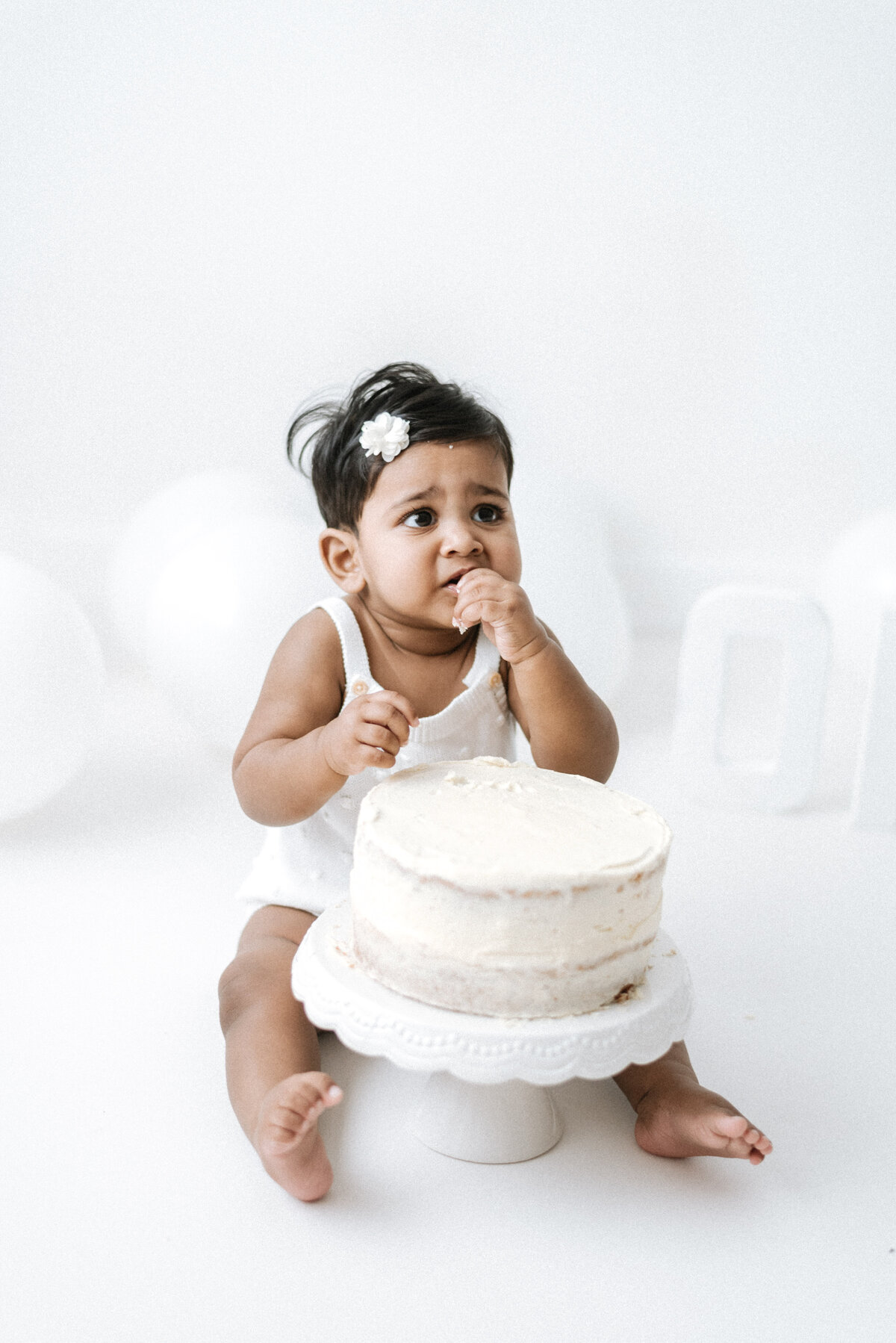 Baby girl eating a cake at billingshurst cake smash photoshoot