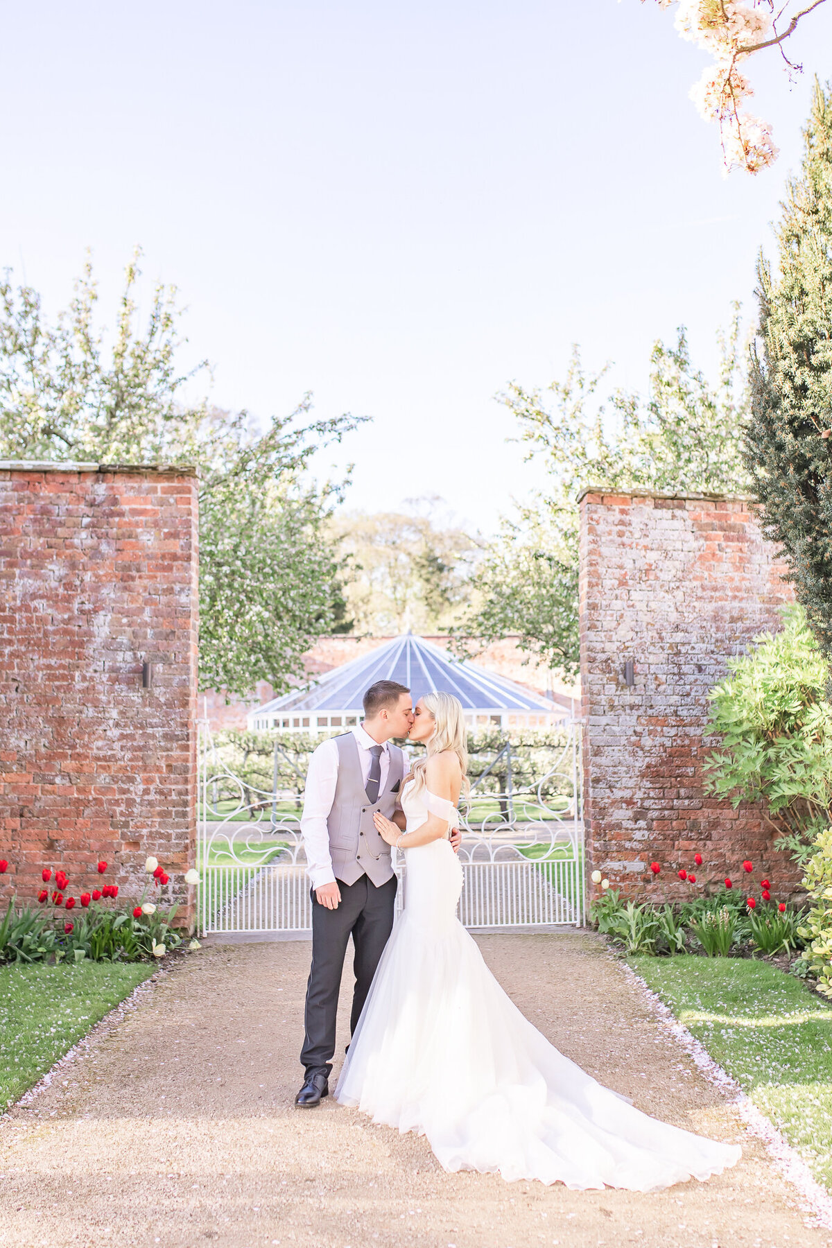 Bride and groom stood outside at Combermere Abbey with the glass house in background