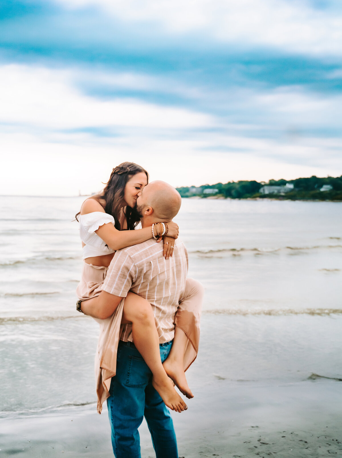 Family Photographer, a woman jumps into her husbands arms at the beach