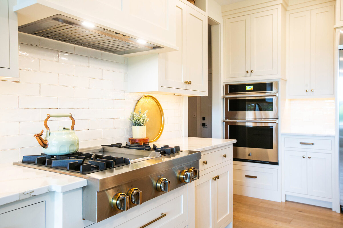 Open kitchen with white cabinets, large island, and quartz countertops in an Otsego custom home