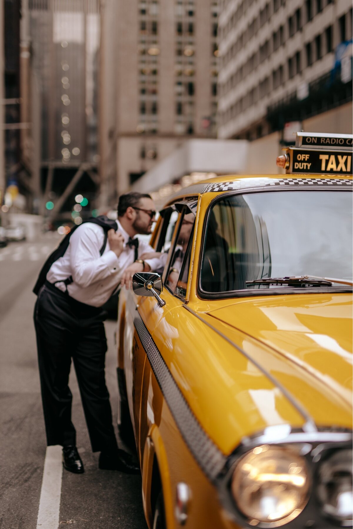 Groom leaning on a vintage Taxi  on NYC streets.