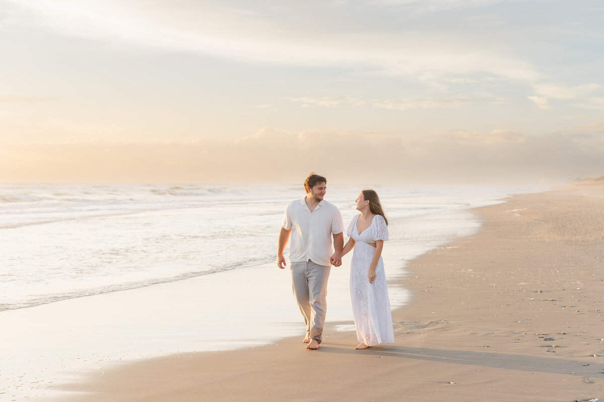 Orlando engagement photographer captures newly engaged couple near the ocean water at sunrise