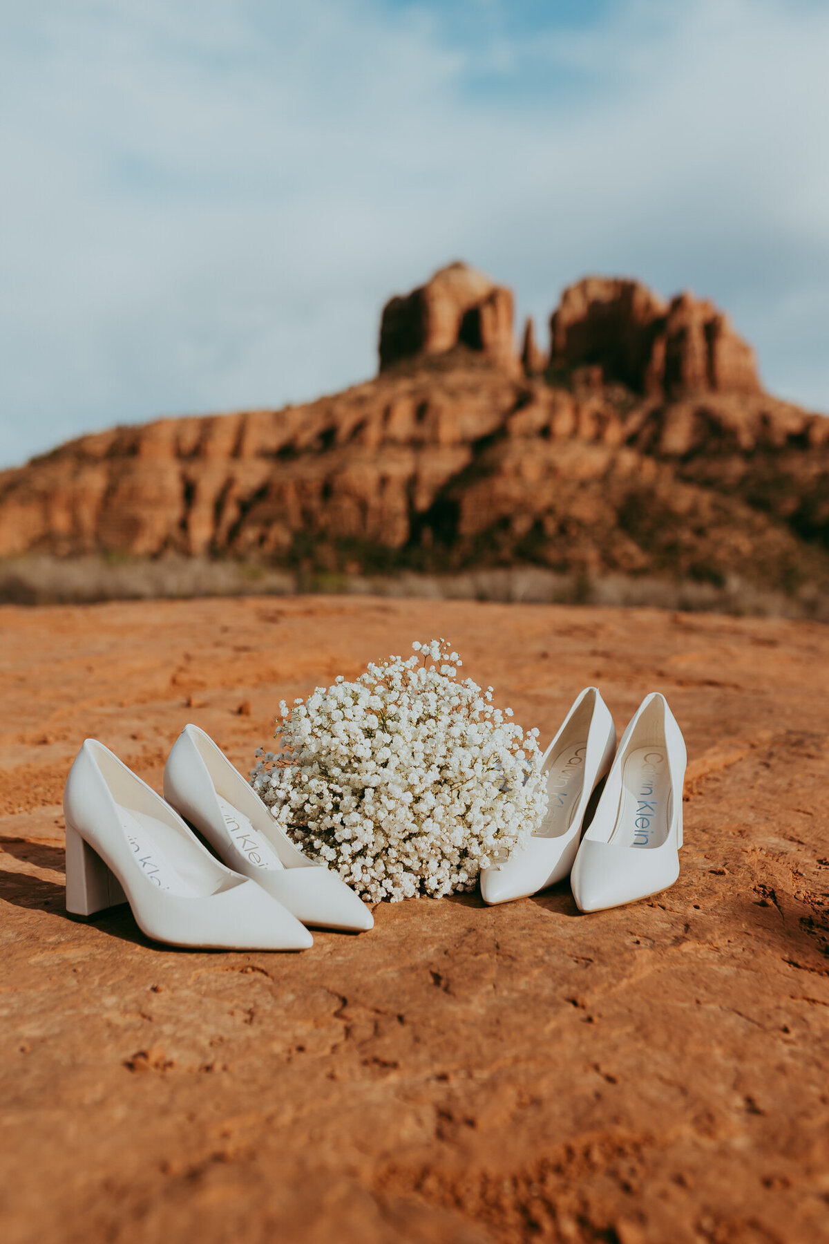 two paris of white heels on sedona backdrop