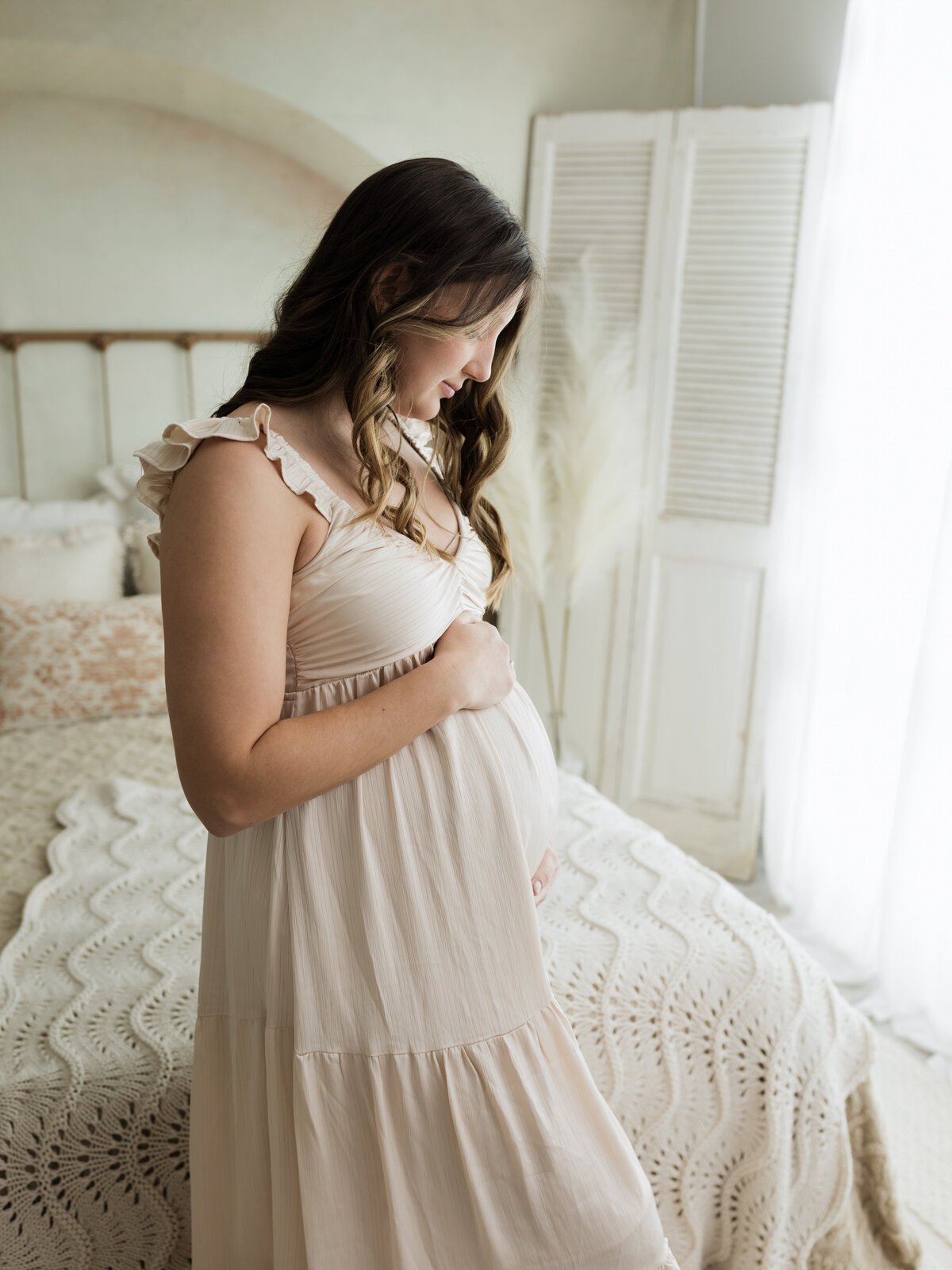 pregnant mother in cream maternity gown holding baby bump for studio maternity photoshoot cleveland maternity photographer