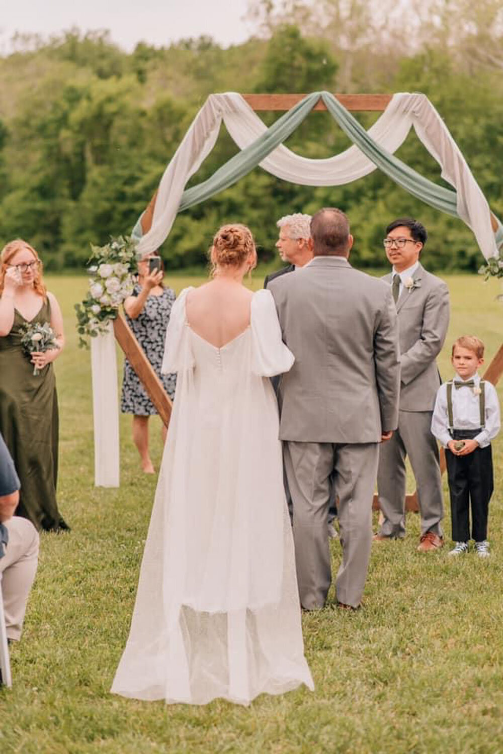 Bride walking down the aisle with a geometric arch