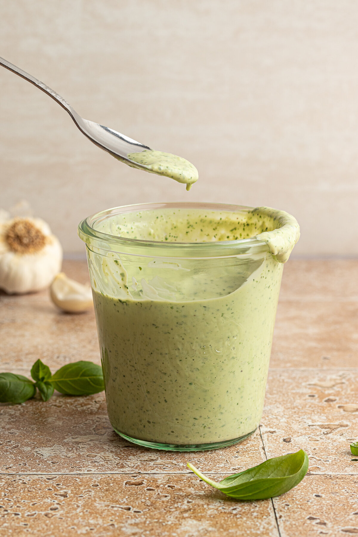 a green dressing in a glass cup being lifted by a spoon