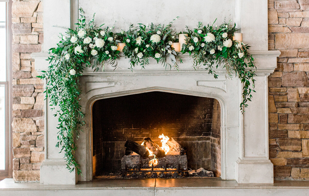 Beautiful fireplace with gorgeous lush florals at The Lakehouse, a romantic sophisticated wedding venue in Calgary, featured on the Brontë Bride Vendor Guide.